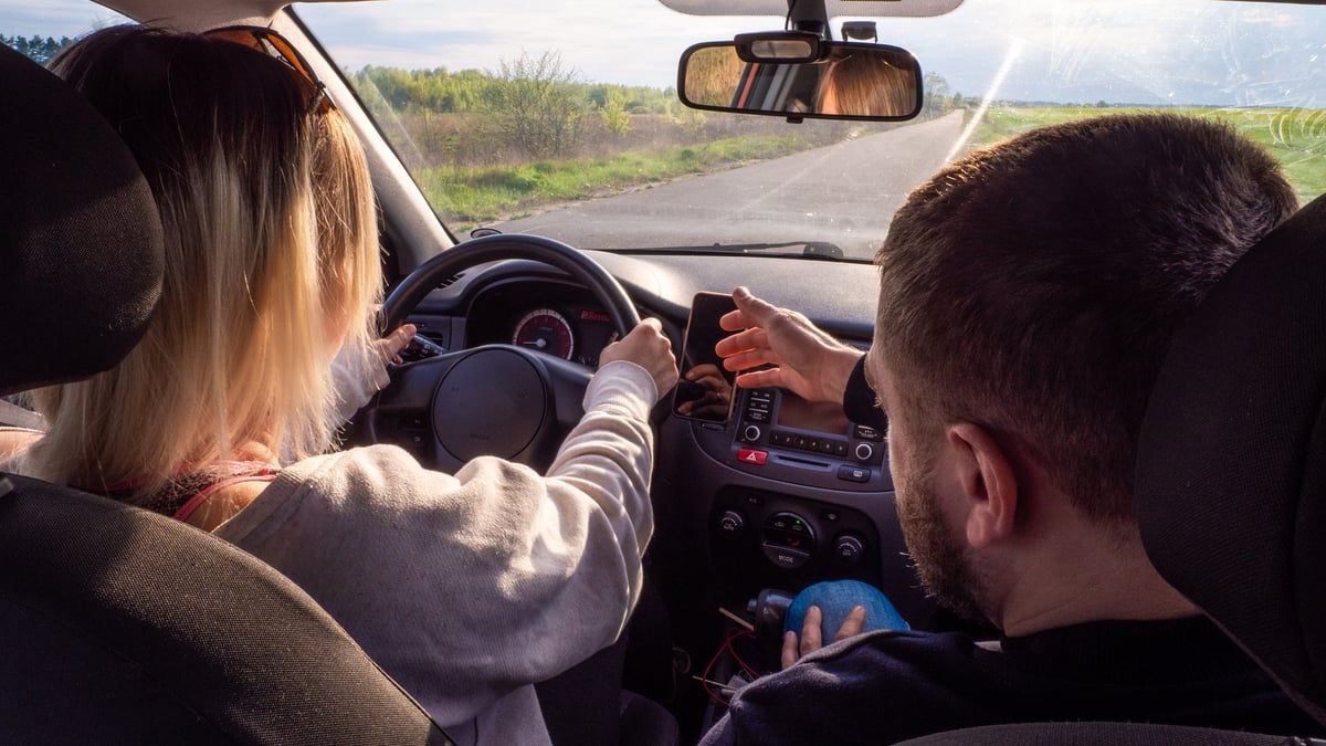 Woman learning to drive for the first time with a professional driving instructor in a car