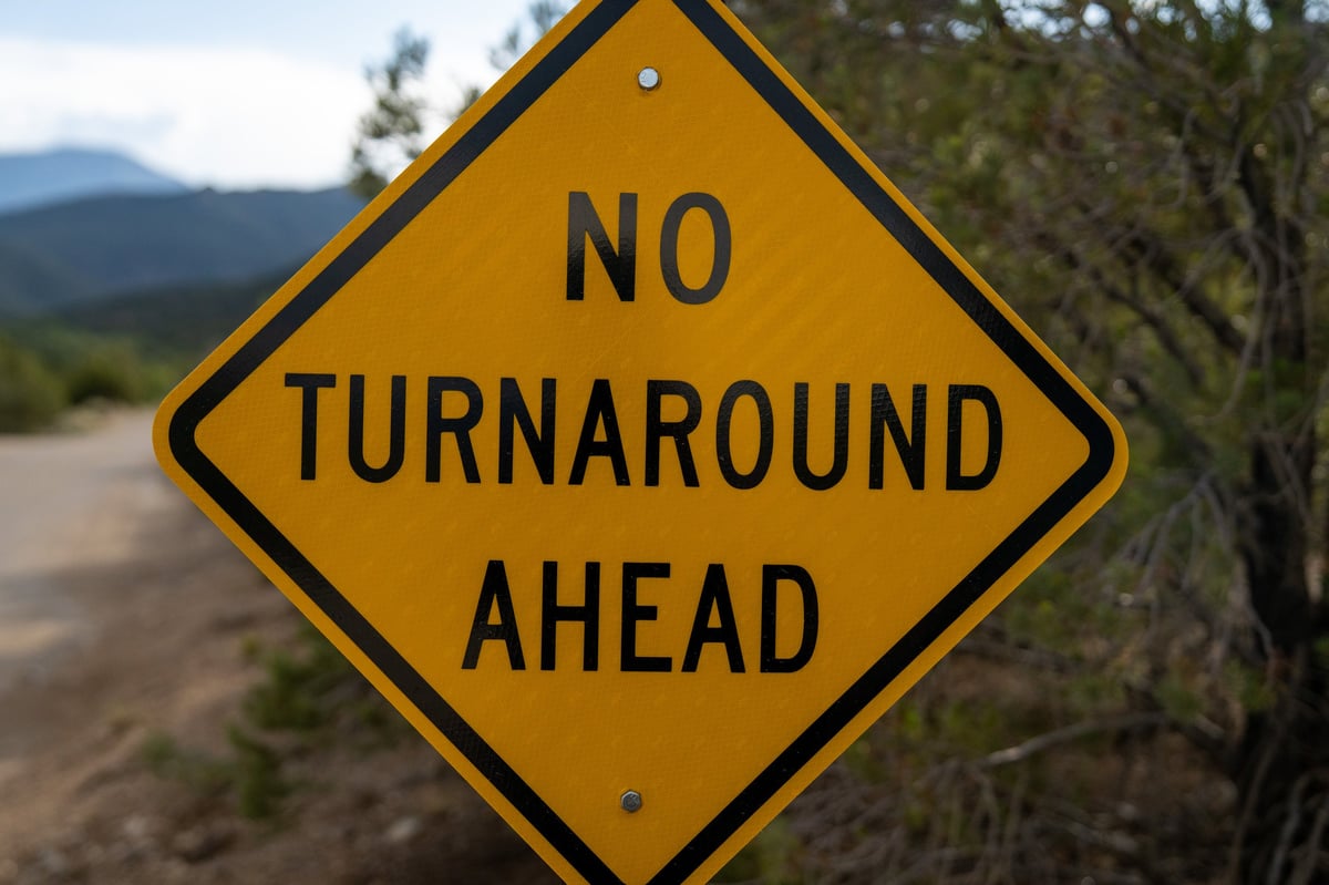Yellow diamond-shaped NO TURNAROUND AHEAD road sign mounted on a metal post, cautioning drivers about limited turnaround space on the route ahead
