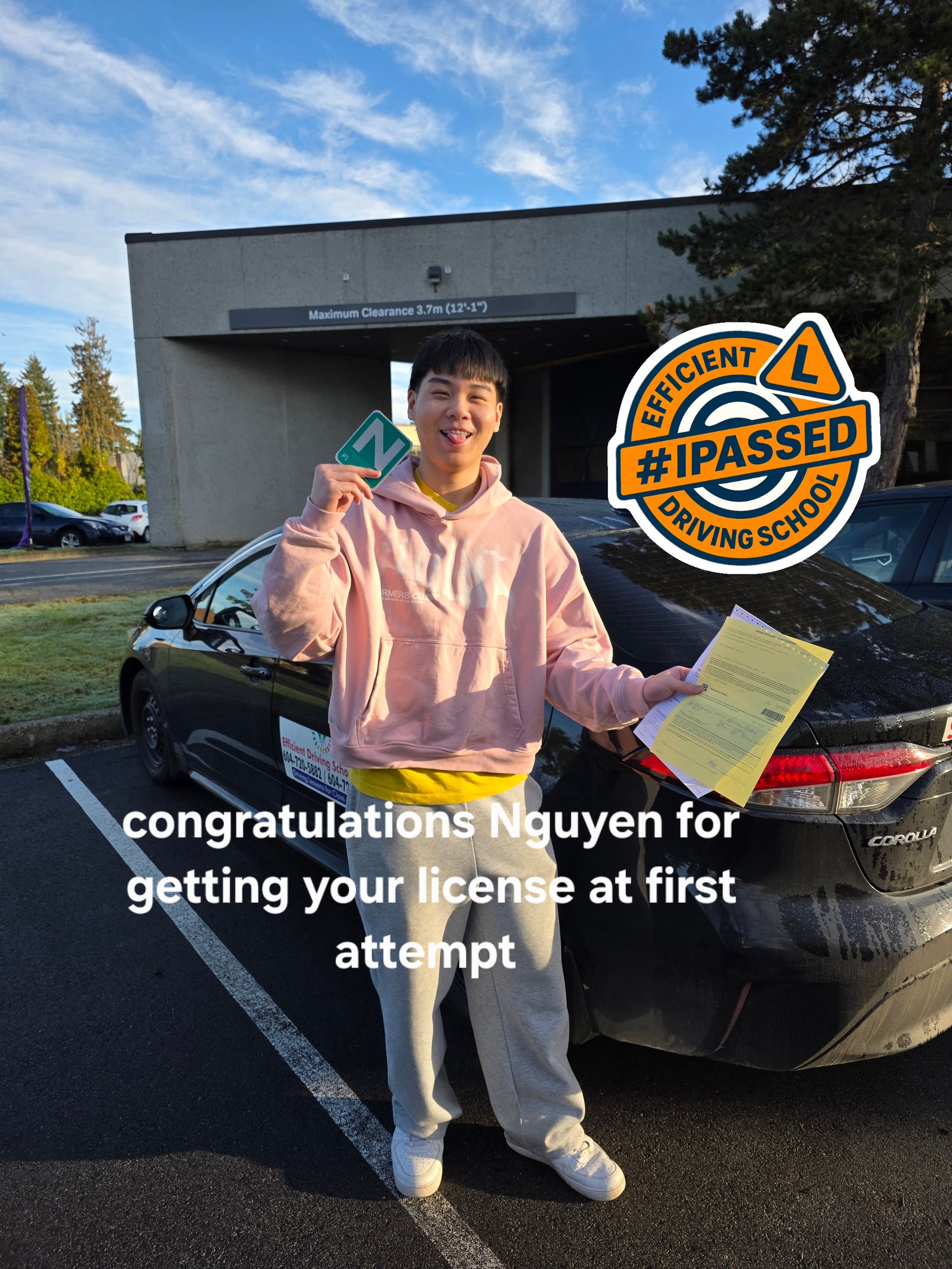 Young person in pink hoodie holding drivers license and test papers next to car, celebrating passing driving test in Langley BC